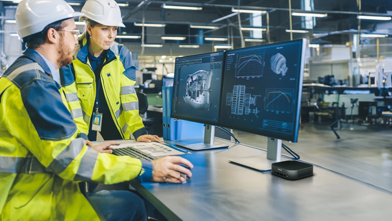 man and woman at desk looking at computer monitors